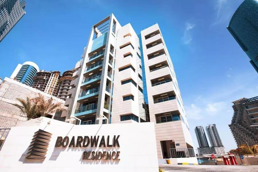 Bright, open-concept modern apartment living room inside Boardwalk Residence with light-toned floors, floor-to-ceiling windows, and panoramic waterfront views of Al Reem Island.